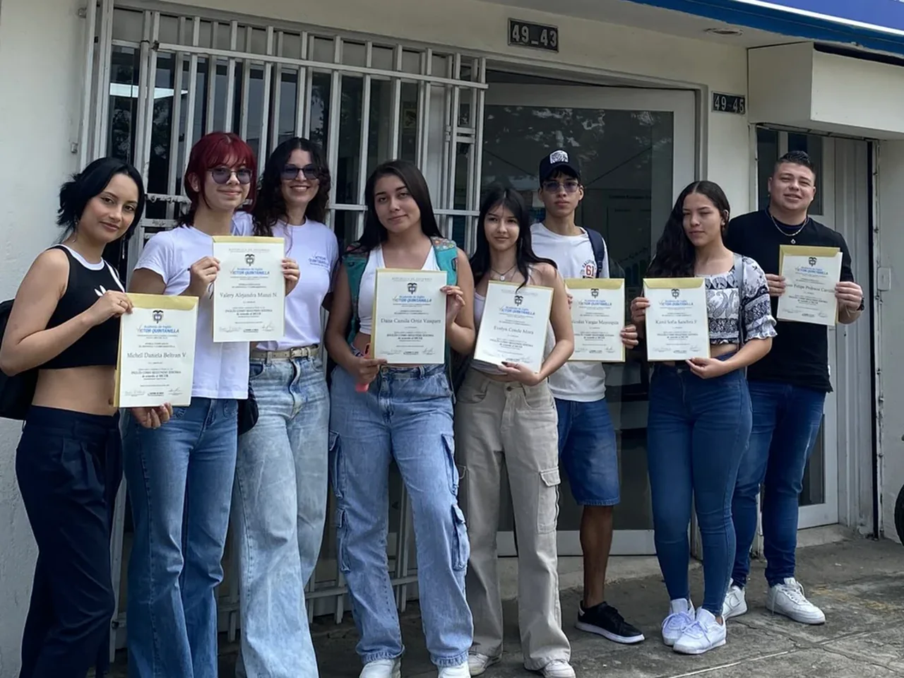 Estudiantes de la Academia de Inglés Víctor Quintanilla con sus diplomas frente a la sede